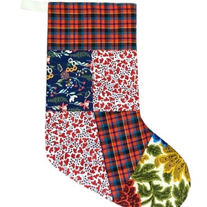 May include: A patchwork Christmas stocking with a red, blue, and green floral pattern. The stocking has a white cuff and a red and blue plaid pattern.