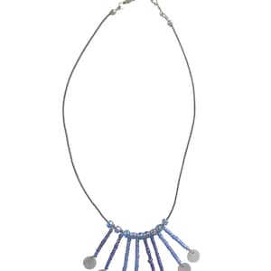 May include: A blue and silver beaded necklace with a pendant of several small, round, silver discs.