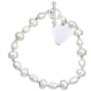 May include: A bracelet featuring a strand of white oval-shaped pearls separated by small silver-toned beads. The piece is secured with a silver-toned toggle clasp and includes a smooth, heart-shaped silver-toned charm hanging from the closure.
