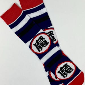 May include: A pair of crew socks with a red cuff and toe, and a blue and white striped pattern. The socks feature a circular emblem with Japanese characters in black.