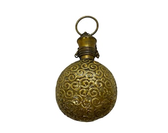 May include: A gold-colored metal bottle with a round, ornate design. The bottle has a small loop at the top for hanging.