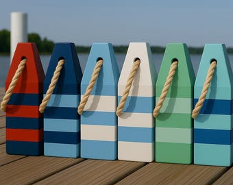 May include: Six colorful wooden buoys with rope handles. The buoys are painted in red, blue, white, and green with horizontal stripes. They are arranged on a wooden dock with a lake and sky in the background. Nautical decor.