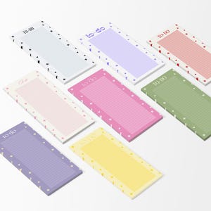 May include: A selection of rectangular notepads in various colours, including white, pink, purple, and yellow. Each notepad has a lined interior and a decorative border with small heart or star patterns. The words "To Do" are printed on some.