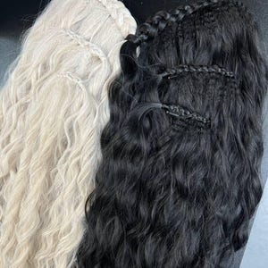 May include: Two hair extension pieces, one platinum blonde and one jet black, featuring a wavy texture. Each piece is constructed with a braided top section that incorporates small clips for attachment, allowing for secure placement in hair.