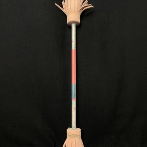 May include: A decorative pencil with a tan leather fringe at both ends. The pencil shaft is multi-colored with a pink stripe. The bottom fringe has the text "reenVibes".