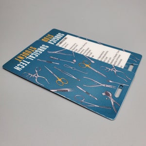 May include: A teal-colored student ID badge with the words "SURGICAL TECH STUDENT" in white and yellow. The badge features illustrations of various surgical instruments, including scissors and forceps.