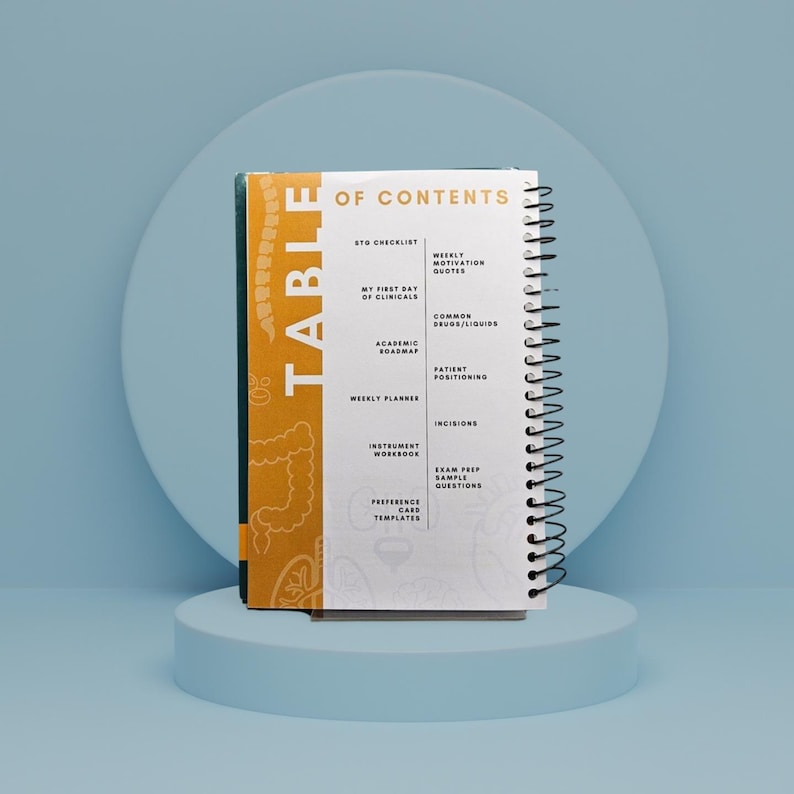 May include: A spiral-bound notebook with a white cover and black spiral binding. The cover features the word "TABLE" in gold lettering and a decorative pattern. The notebook's contents include checklists, weekly planners, and exam prep questions.