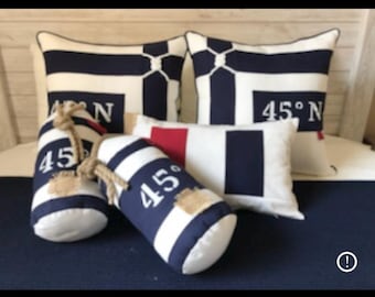 May include: Nautical-themed decorative pillows and buoy-shaped accents in navy blue and white stripes. The pillows feature the text "45° N". The buoy accents have rope handles and patches.