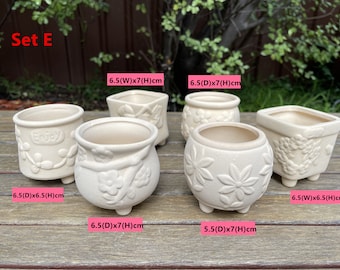 May include: Set of six white ceramic flower pots with different designs. The pots are 6.5 inches in diameter and 6.5 inches tall. The pots have a variety of floral designs and the words "Enjoy" are printed on one of the pots.