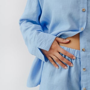 May include: A light blue linen pajama set with a button-up shirt and shorts.
