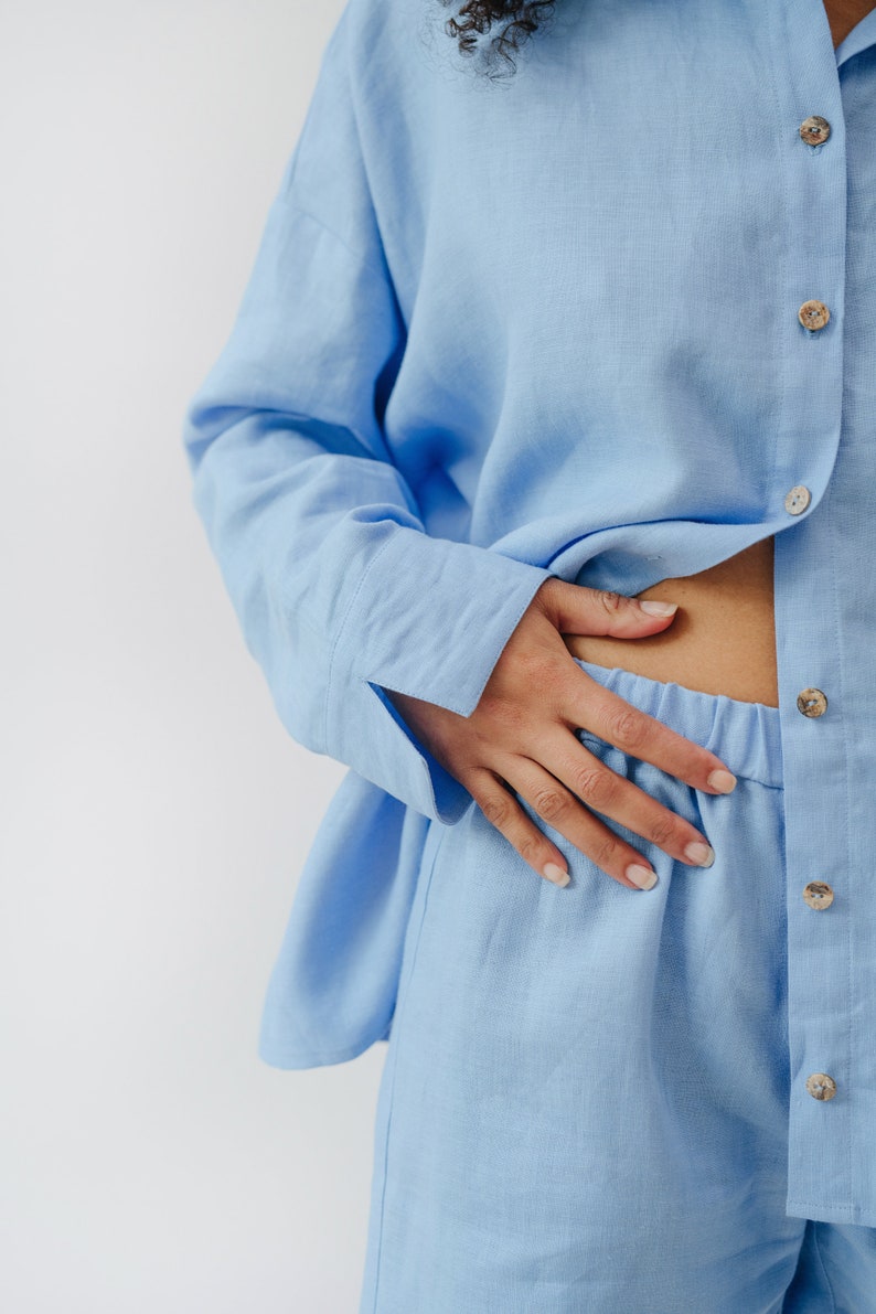 May include: A light blue linen pajama set with a button-up shirt and shorts.