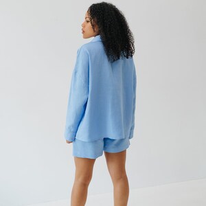 May include: A light blue linen shirt and shorts set. The shirt has a collared neckline and long sleeves. The shorts are a relaxed fit with a straight leg.