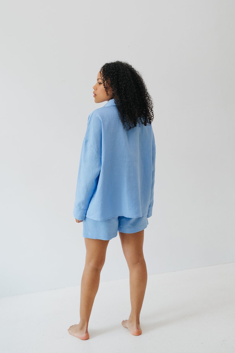 May include: A light blue linen shirt and shorts set. The shirt has a collared neckline and long sleeves. The shorts are a relaxed fit with a straight leg.