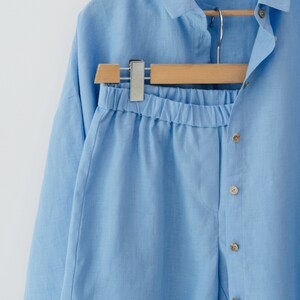 May include: A light blue linen shirt and shorts set. The shirt has a collar and button closure. The shorts have an elastic waistband.