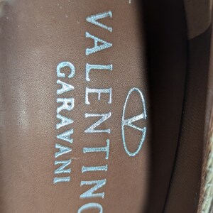 Puede incluir: Primer plano del interior de un zapato con el texto "VALENTINO GARAVANI" y un &oacute;valo peque&ntilde;o con la letra "V" dentro.