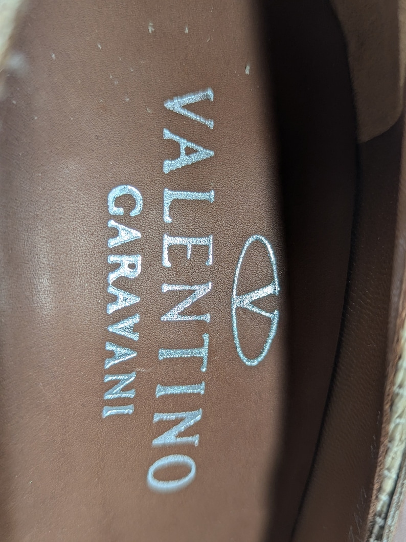 Puede incluir: Primer plano del interior de un zapato con el texto "VALENTINO GARAVANI" y un &oacute;valo peque&ntilde;o con la letra "V" dentro.