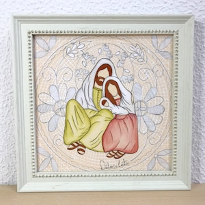 May include: A framed illustration of a Holy Family with a white background and a decorative border. The illustration depicts a man, woman, and child in a loving embrace. The man is wearing a yellow robe, the woman is wearing a red robe, and the child is wearing a white robe. The illustration is signed "Dilaria Costa".