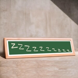 May include: A rectangular chalkboard with a wooden frame. The chalkboard is green with the word "Zzzzzzzzz" written in white chalk. The board is leaning against a neutral-colored wall.