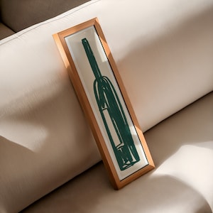 May include: A framed illustration of a green bottle with a white label. The frame is made of natural wood and has a light brown finish.