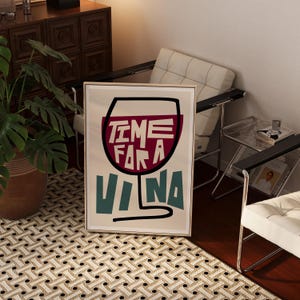 May include: A framed art print with a white background and a black outline of a wine glass. The glass is filled with red wine and the text "TIME FOR A VINO" is written in black and red letters inside the glass.