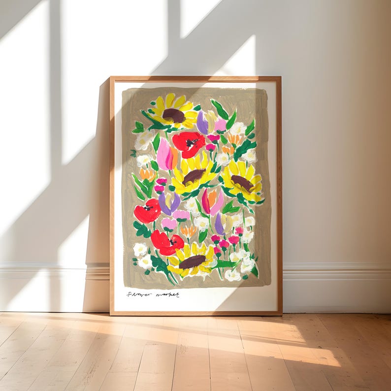 Op de afbeelding: Een ingelijste kunstprint met een kleurrijk bloemstuk. Het kunstwerk toont zonnebloemen, klaprozen en andere bloemen in geel, rood, roze en paarse tinten. De print staat tegen een neutrale achtergrond en is gesigneerd "Flower market".