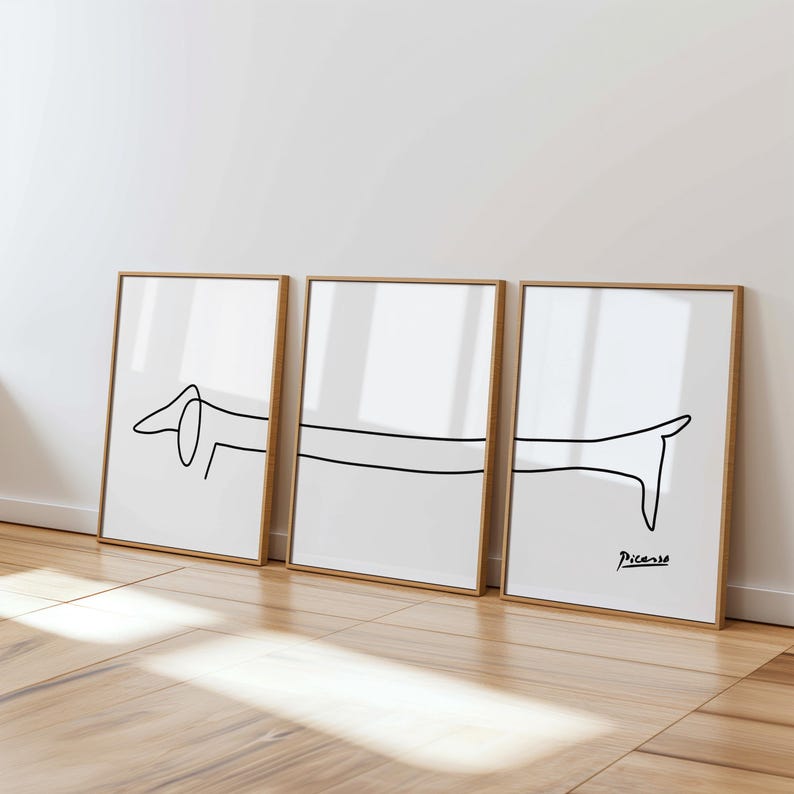 May include: Three framed prints of a line drawing of a dachshund dog. The prints are in black and white and are arranged in a row. The print on the right has the signature "Picasso" in the bottom right corner.