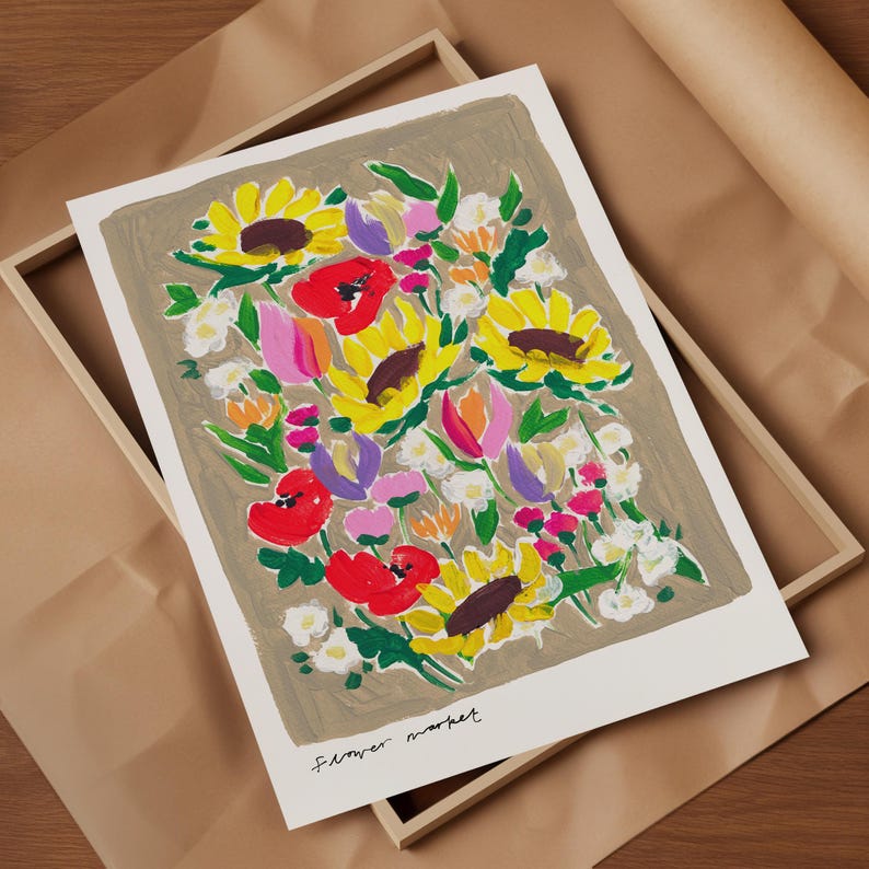 Op de afbeelding: Een bloemenkunstprint met een levendig boeket zonnebloemen, klaprozen en andere bloemen in geel, rood, roze en paars. De print staat tegen een neutrale achtergrond en is ingelijst in een houten kist. De tekst "Flower market" staat onderaan.