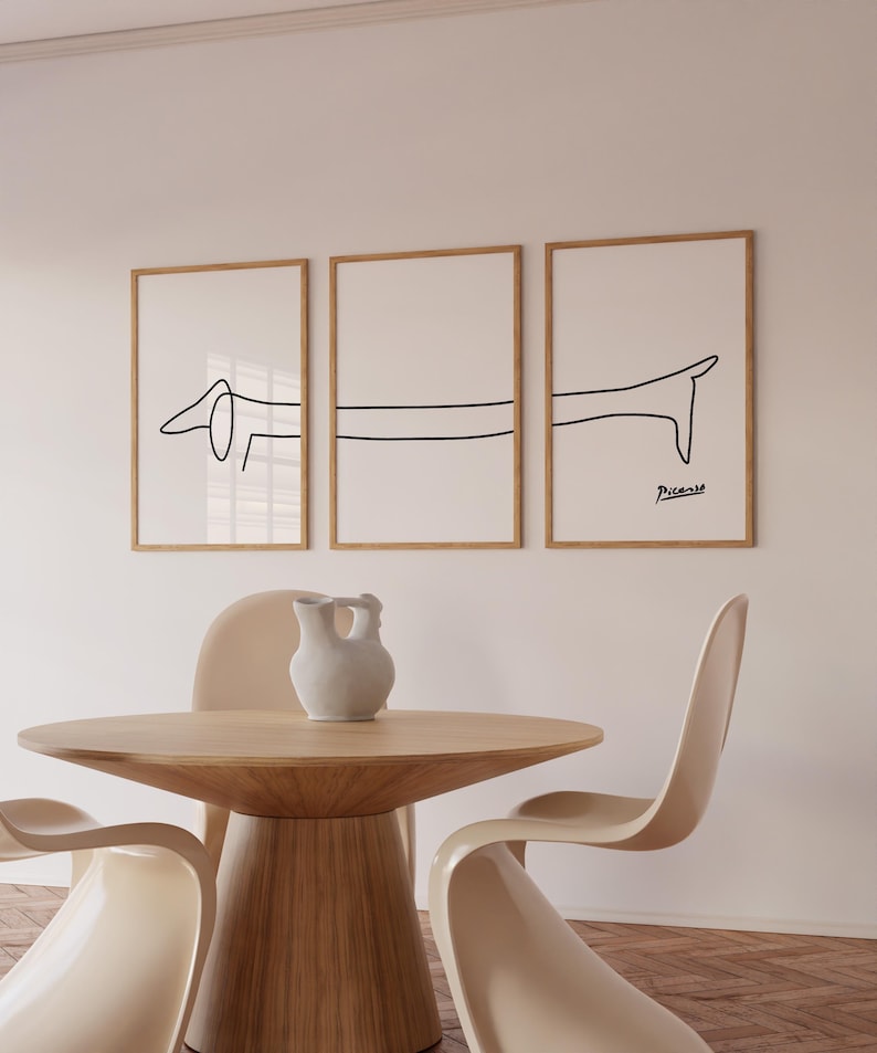 May include: Three framed black and white line drawings of a dachshund dog. The drawings are in a minimalist style and are hung on a white wall. The bottom drawing is signed "Picasso".