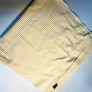 May include: A beige and white striped fabric with a small black tag that says "O.G." on it.