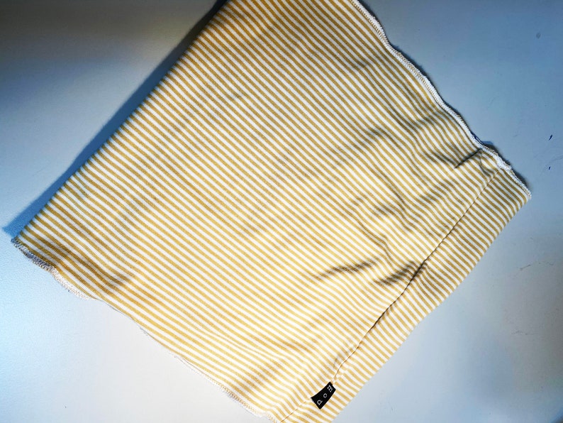 May include: A beige and white striped fabric with a small black tag that says "O.G." on it.