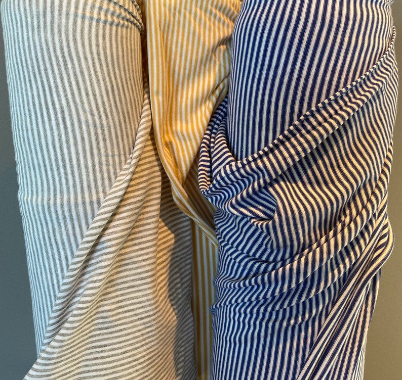 May include: Three rolls of striped fabric. One roll is white and gray, one is yellow and white, and one is navy blue and white.