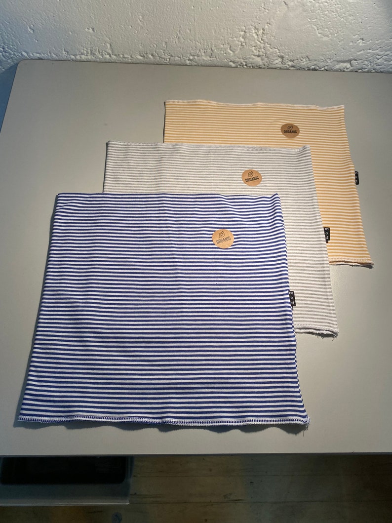 May include: Three striped fabric headbands in blue and white, gray and white, and yellow and white. Each headband has a small brown tag with the word "organic" printed on it.