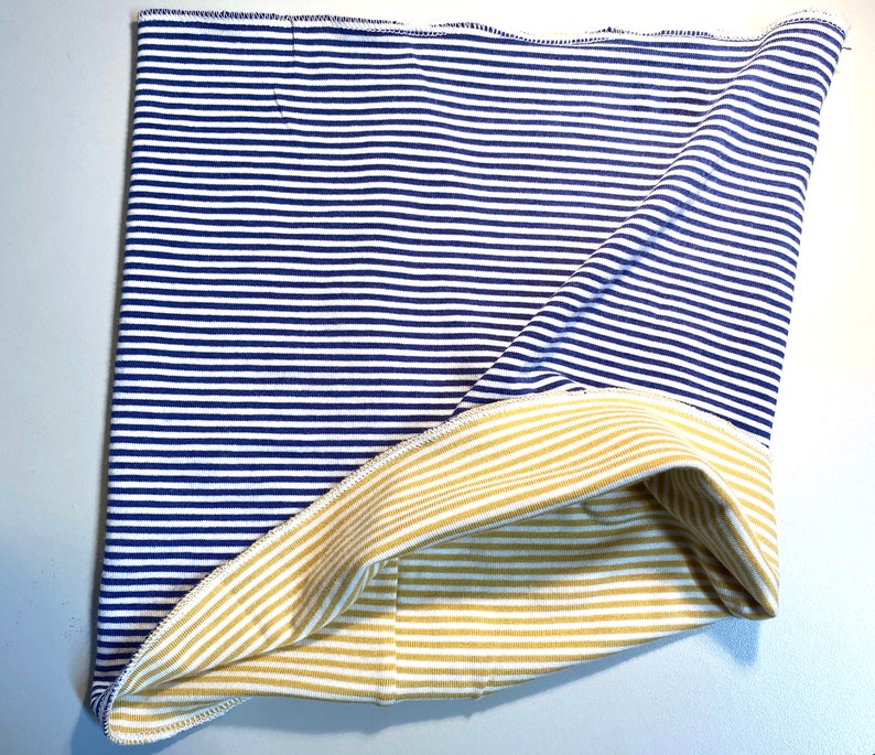 May include: A reversible fabric headband with blue and white stripes on one side and yellow and white stripes on the other side.