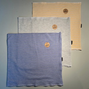 May include: Three striped fabric neck warmers in blue, gray, and yellow with a brown organic label on each.