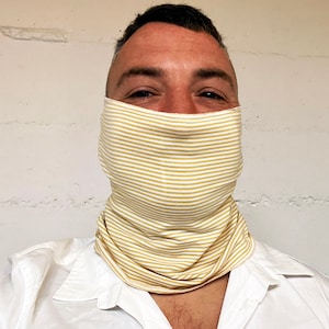May include: A person wearing a white shirt and a yellow and white striped face covering.