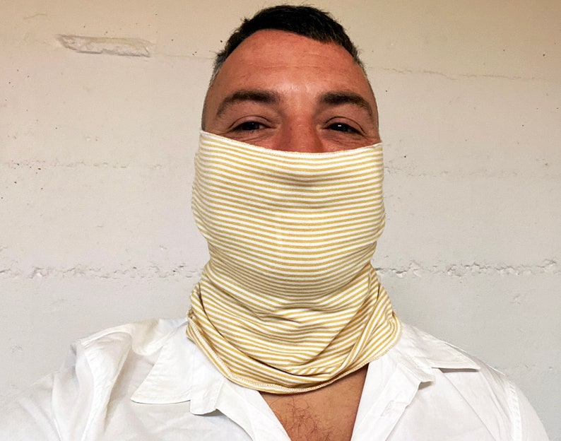 May include: A person wearing a white shirt and a yellow and white striped face covering.