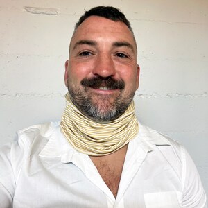 May include: A man wearing a white shirt with a yellow and white striped neck gaiter.