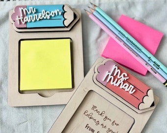 May include: Two wooden pencil-shaped note holders with a sticky note pad. The top of each holder has a personalized name, "Mr. Harrelson" and "Ms. Minar". The bottom of each holder has a space for a message. One message reads "Thank you for helping me grow! From, Emit 2024".