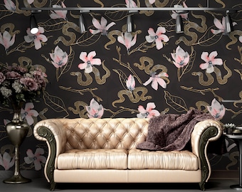 May include: A gold and black patterned wallpaper with a floral design featuring pink flowers and snakes. A tan leather sofa with a brown throw blanket sits in front of the wallpaper.