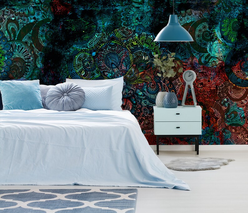 May include: A bedroom with a blue and green patterned wallpaper featuring intricate designs. The bed has a light blue duvet and pillows. A bedside table with a lamp and a clock is next to the bed.
