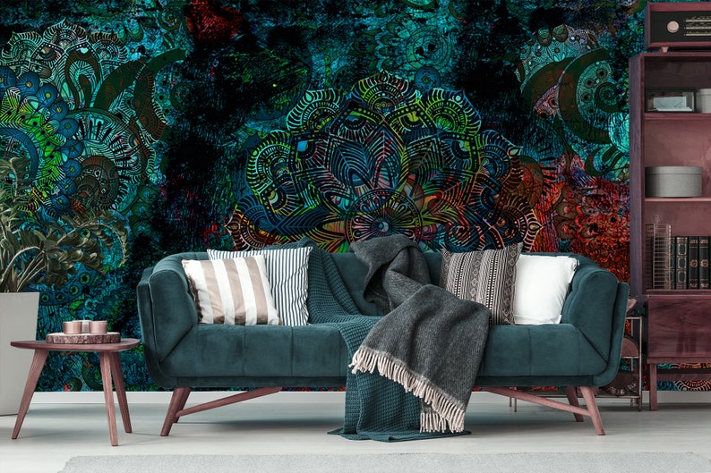 May include: A teal blue velvet sofa with a grey throw blanket and striped cushions in front of a colourful abstract wall mural.