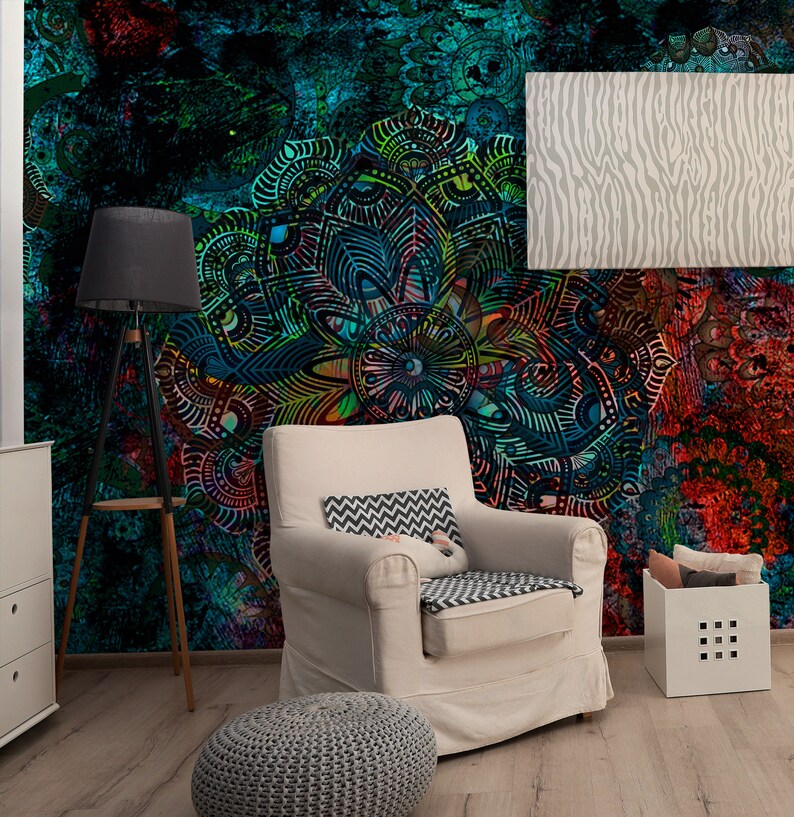 May include: A white armchair with a grey and white patterned cushion sits in a room with a colourful mandala wall mural. A grey floor lamp and a grey ottoman are also in the room.