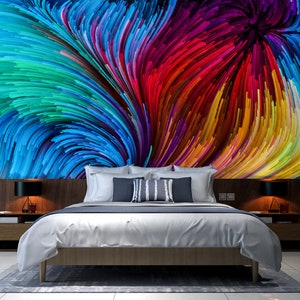 Pu&ograve; includere: Una camera da letto con un letto bianco e una stampa d'arte astratta colorata sul muro. La stampa presenta linee vorticose di blu, verde, rosso, giallo e viola.