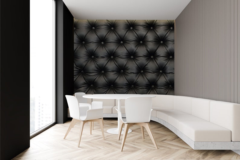 May include: A white curved sofa with a white table and four white chairs in a modern dining room with a black tufted wall.