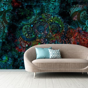 May include: A brown couch with two pillows, one blue and one with a white and blue pattern, sits in front of a wall with a colorful, abstract mandala design.