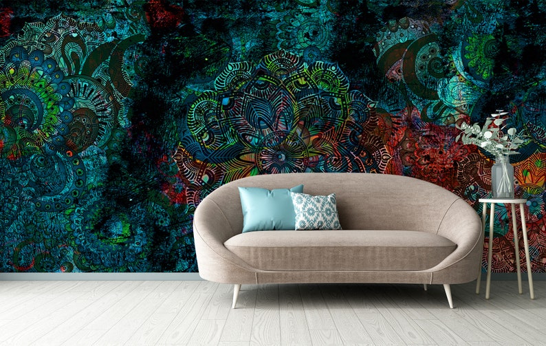 May include: A brown sofa with two cushions, one blue and one with a white and blue pattern, sits in front of a wall with a colourful, abstract mandala design.