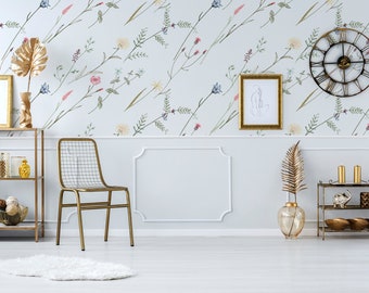 May include: A white wall with a floral wallpaper pattern featuring delicate flowers and leaves in shades of pink, blue, and green. The wall is decorated with a gold framed picture, a gold clock, and a gold metal shelf with decorative items.