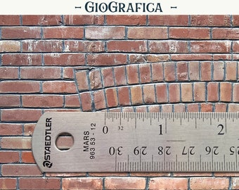 May include: A close-up of a red brick wall with a ruler measuring 2 inches. The ruler is labeled "STAEDTLER MARS 963 53-12".