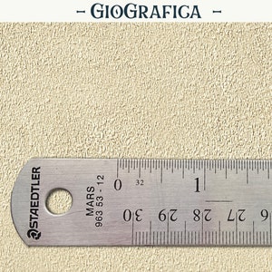 May include: A close-up of a beige textured surface with a metal ruler measuring 2 inches. The ruler is labeled "Staedtler Mars 963 53-12" and has markings for 1/16 inches.