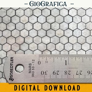 Puede incluir: Primer plano de un patrón de azulejos hexagonales blancos con líneas de lechada negras. Una regla se coloca encima de los azulejos, mostrando medidas en centímetros. La regla está etiquetada como "Staedtler Mars 963 53-12".
